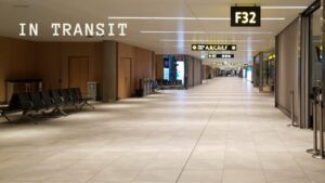 Empty airport terminal corridor at night with gate F32 sign, showing closed shops and vacant seating areas